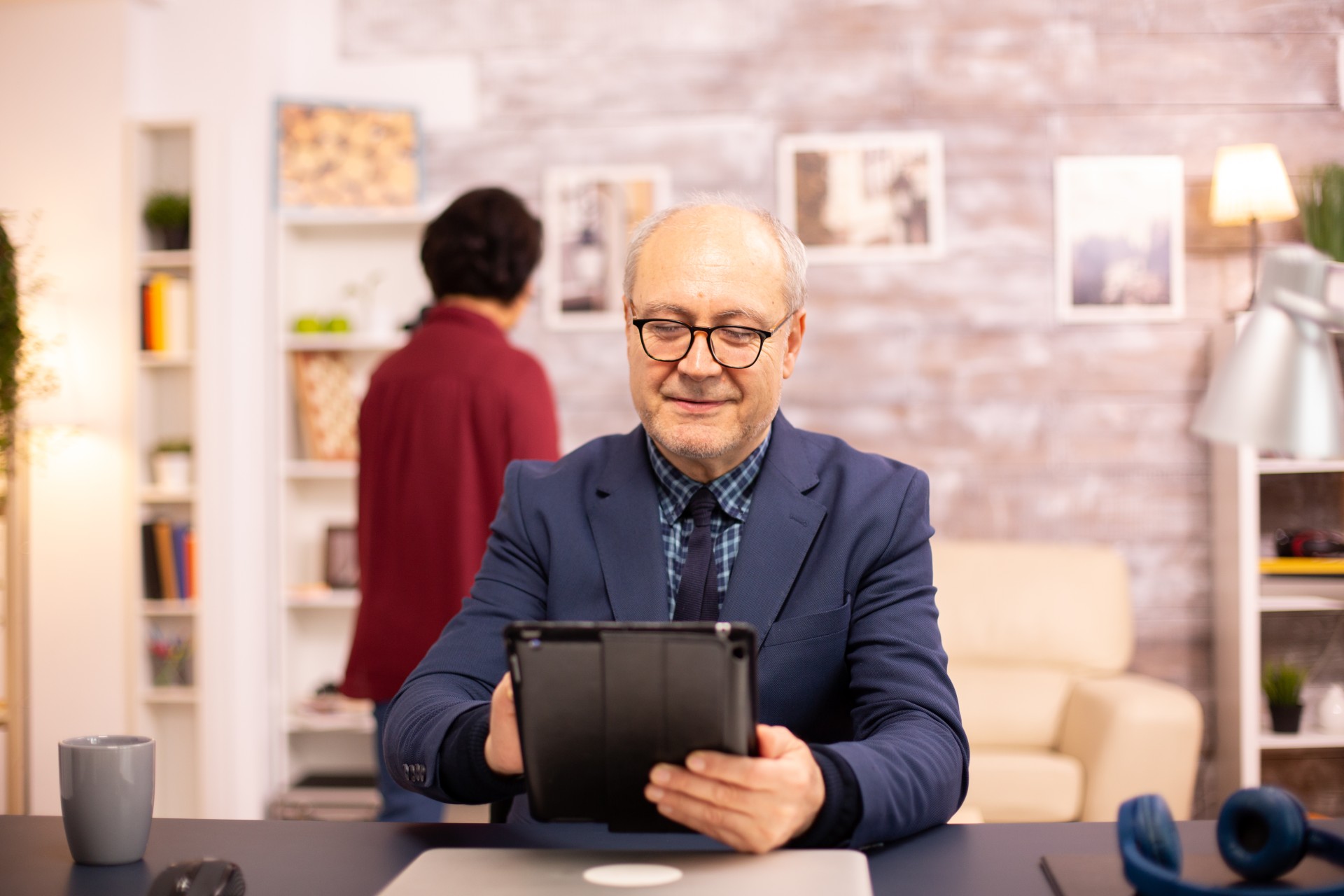 Senior man in his 60s using a modern digital tablet in his cozy home